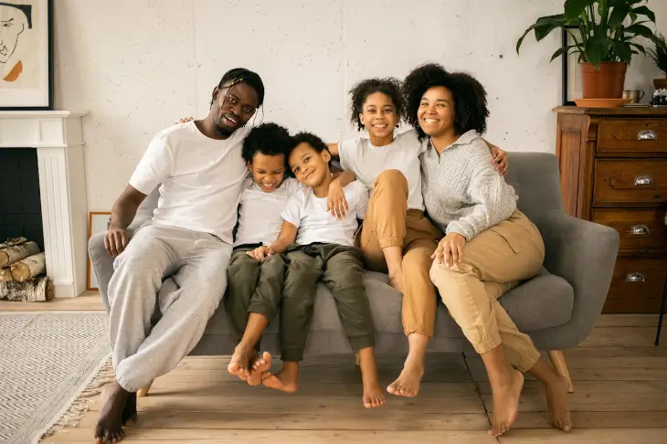 Famille réunionnaise souriante assise sur un canapé dans un salon
