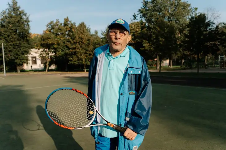 Homme senior tenant une raquette de tennis sur un court en extérieur