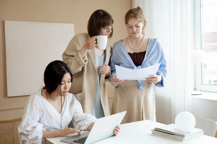 Trois salariées consultent des documents administratifs dans un bureau