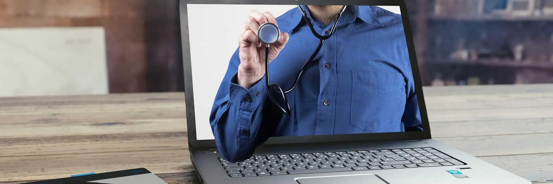 Un docteur tenant un stéthoscope a travers un ordinateur portable
